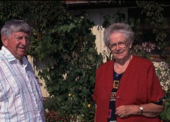 En äldre man och kvinna framför en grön buske