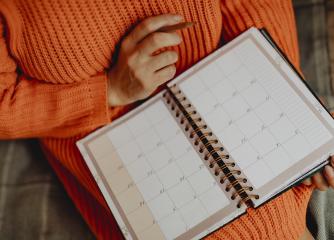 En person i orange tröja med en kalender i knät