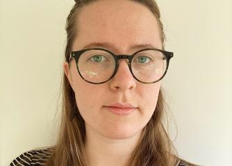 Leende kvinna med långt brunt hår och glasögon